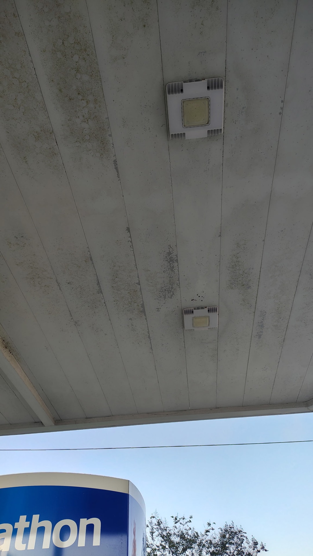 Gas station canopy ceiling covered in dirt and mildew before pressure washing